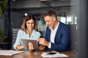 Consultant showing a client a digital product on a tablet and smiling.