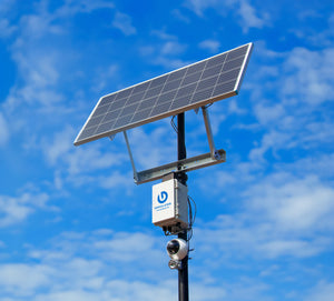 Gridless solar sentry surveillance pole for remote security cameras against blue sky background.